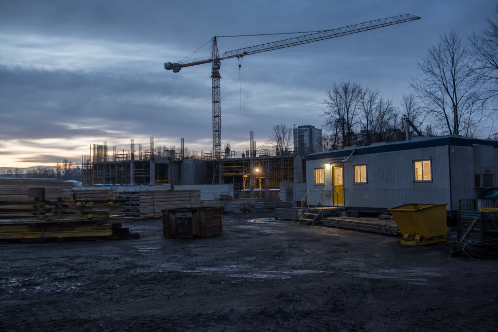 Chantier de construction à l’aube avec grue et roulotte éclairée